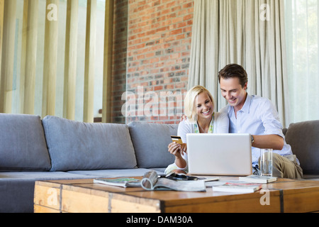 Couple shopping online sur canapé Banque D'Images