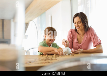 Mère et fille filling piggy bank Banque D'Images