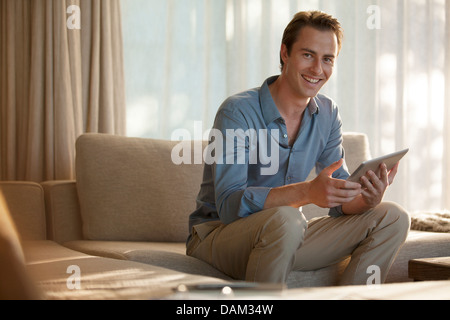 Man using tablet computer on sofa Banque D'Images