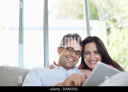 Couple using tablet computer on sofa Banque D'Images