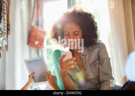 Les femmes utilisant l'ordinateur tablette et téléphone cellulaire dans la chambre Banque D'Images