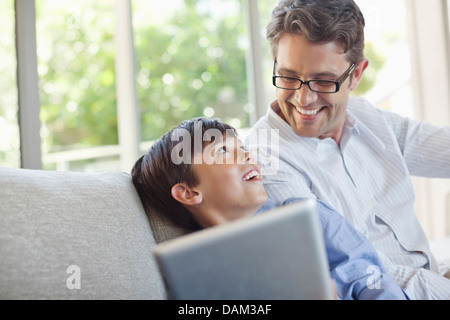 Père et fils using tablet computer on sofa Banque D'Images