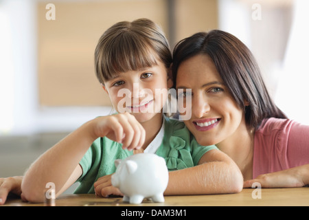 Mère et fille filling piggy bank Banque D'Images