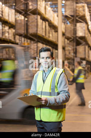 Worker writing on clipboard in warehouse Banque D'Images