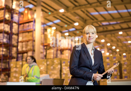 Businesswoman using clipboard in warehouse Banque D'Images