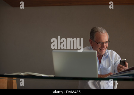 Businessman using cell phone at desk Banque D'Images