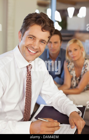 Conseiller financier smiling with couple on sofa Banque D'Images