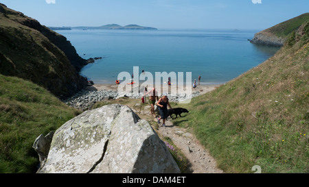 Couple avec un chien de quitter la plage où les gens sont le kayak à Pembrokeshire Wales UK Meigan Porth Banque D'Images