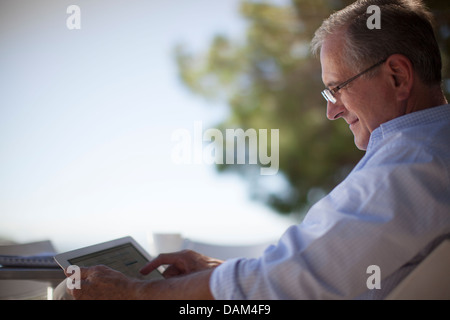 Older Man using tablet computer outdoors Banque D'Images