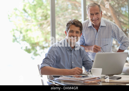 Homme plus âgé et plus jeune homme woman smiling at desk Banque D'Images