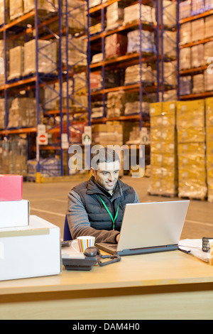 Worker using laptop in warehouse Banque D'Images