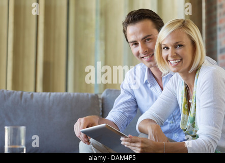 Couple using tablet computer on sofa Banque D'Images