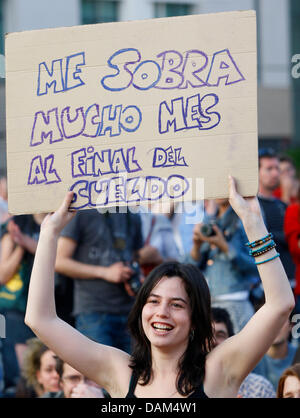 Une femme est titulaire d'un signe 'Me sobra mes mucho al final del sueldo" lors d'un rassemblement concerné avec les manifestations en cours en Espagne devant la porte de Brandebourg à Berlin, Allemagne, 21 mai 2011. Sous la devise 'Democracia Real Ya !" plusieurs centaines de personnes, la plupart des Espagnols, ont été mobilisées grâce à Facebook de se rassembler à Pariser Platz afin de lutter pour plus de démocratie. Photo : Florian Banque D'Images