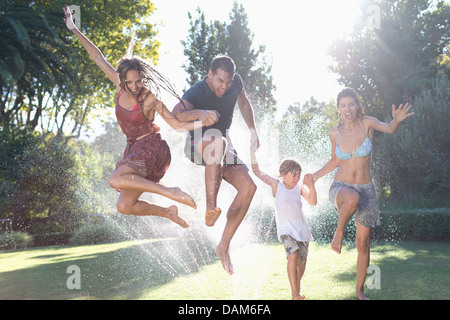 Family jumping en réseau sprinkleur Banque D'Images