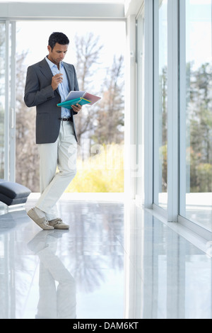 Businessman reading papers in office Banque D'Images