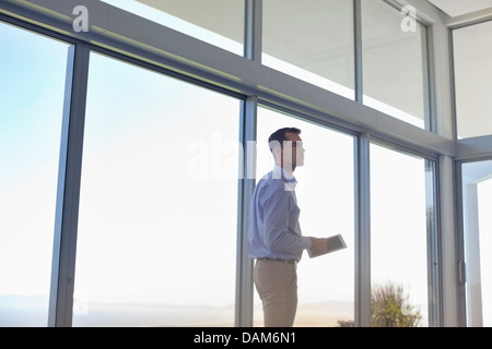 Businessman using tablet computer at window Banque D'Images