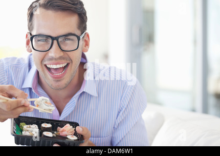 Businessman eating sushi in office Banque D'Images