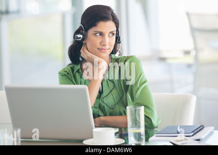 Businesswoman wearing headphones at desk Banque D'Images