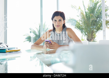 Businesswoman using cell phone in office Banque D'Images