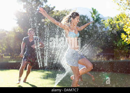 Couple playing in backyard sprinkleur Banque D'Images