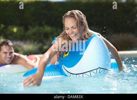 Femme jouant sur inflatable toy in swimming pool Banque D'Images