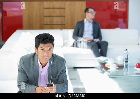 Businessman listening to headphones on sofa Banque D'Images