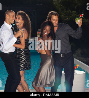 Friends dancing by swimming pool at party Banque D'Images