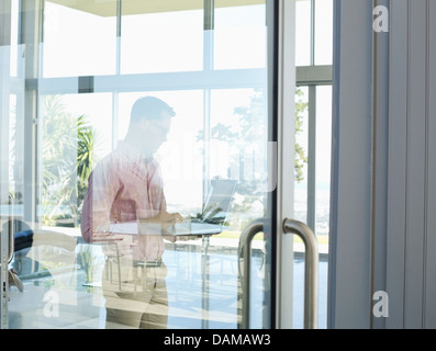 Businessman using tablet computer at office window Banque D'Images