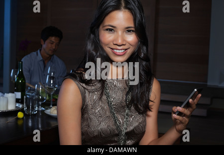 Woman using cell phone at party Banque D'Images