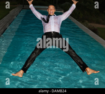 Toute habillée man jumping into swimming pool Banque D'Images