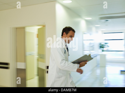 Dossier médical Médecin lecture in hospital hallway Banque D'Images