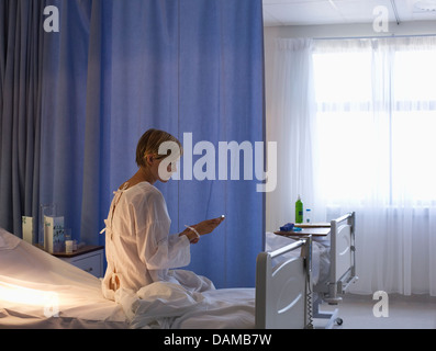 Patient using cell phone in hospital bed Banque D'Images