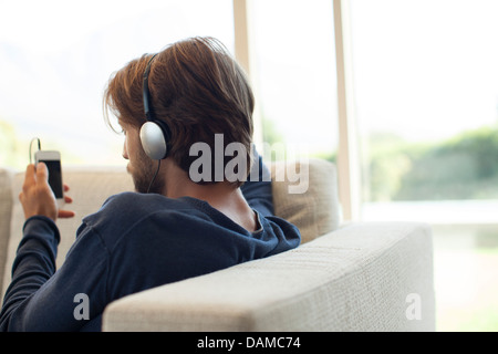 Man listening to headphones on sofa Banque D'Images