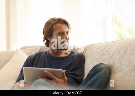 Man using tablet computer on sofa Banque D'Images