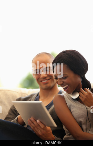 Couple using tablet computer on sofa Banque D'Images