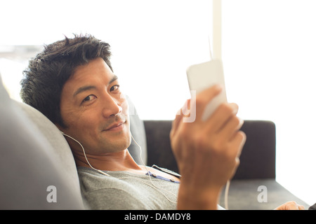 Man listening to headphones on sofa Banque D'Images