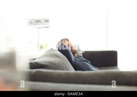 Smiling man relaxing on sofa Banque D'Images