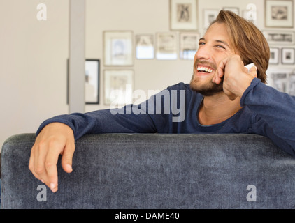 Man talking on cell phone on sofa Banque D'Images