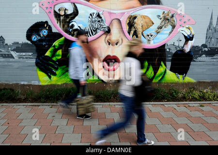 Les piétons passent devant un mur de graffiti situé à une à Cologne, Allemagne, 23 juin 2011. L'image est une publicité du zoo de Cologne. Photo : Marius Becker Banque D'Images