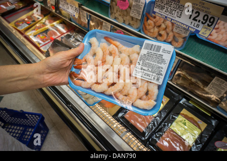 Un client parcourt les crevettes en provenance de la Malaisie dans un supermarché réfrigérateur cas à New York Banque D'Images