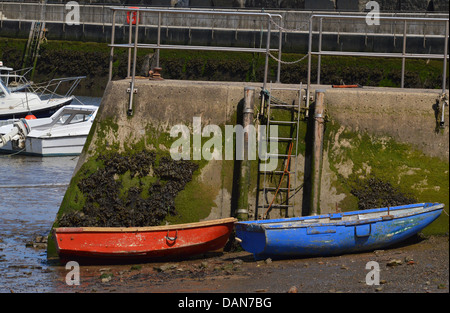 2 petits bateaux - un rouge , un bleu - amarré à Staithes Harbour Beach , North Yorkshire Banque D'Images