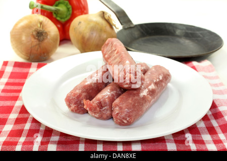 Saucisses crues sur une plaque blanche Banque D'Images