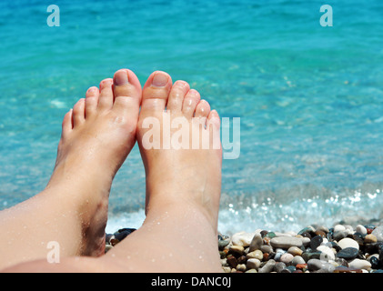 Jeune femme pieds sur la plage avec l'eau bleue Banque D'Images