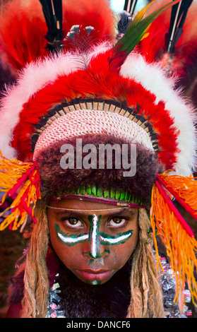 Jeune fille avec son visage peint et portant une large coiffe traditionnelle à l'Goroka show en Papouasie Nouvelle Guinée. Banque D'Images