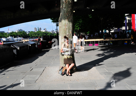 Une femme lisant un journal, South Bank, Londres, UK Banque D'Images