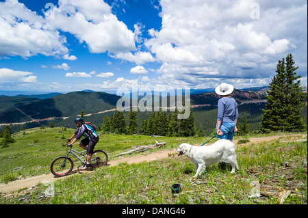 Femme seule & Platinum Golden Retriever dog watch un mâle du vélo de montagne sur le monarque Crest Trail, le centre du Colorado, USA Banque D'Images