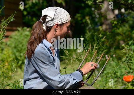 L'aide jardinier de la laine d'acier pour éliminer la rouille d'un outil de jardin de l'Oregon dans la vallée de Wallowa. Banque D'Images