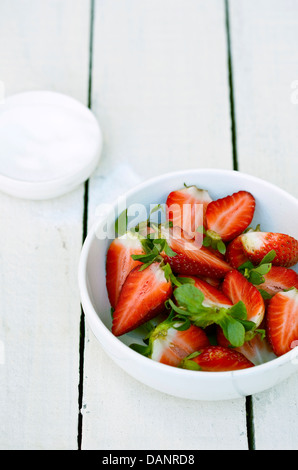 Un bol de fraises rouges frais sur un tableau peint en blanc. Banque D'Images