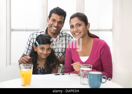 Les parents aident leur enfant avec son travail à domicile. La famille indienne dans la cuisine de détente. Banque D'Images