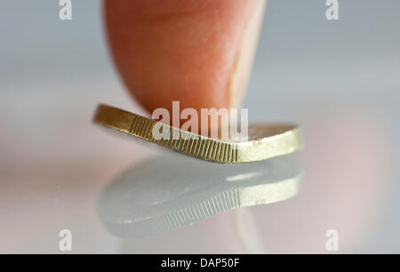 Fichier - ILLUSTRATION - une archive photo datée du 4 juin 2011 montre un bent One-Euro-coin sous un pouce à Francfort/Main, Allemagne. Photo : Frank Rumpenhorst Banque D'Images